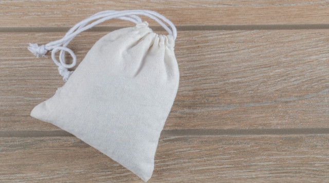 Невеликий мішечок з натуральної тканини, наповнений білим або тростинним цукром - фото 560262